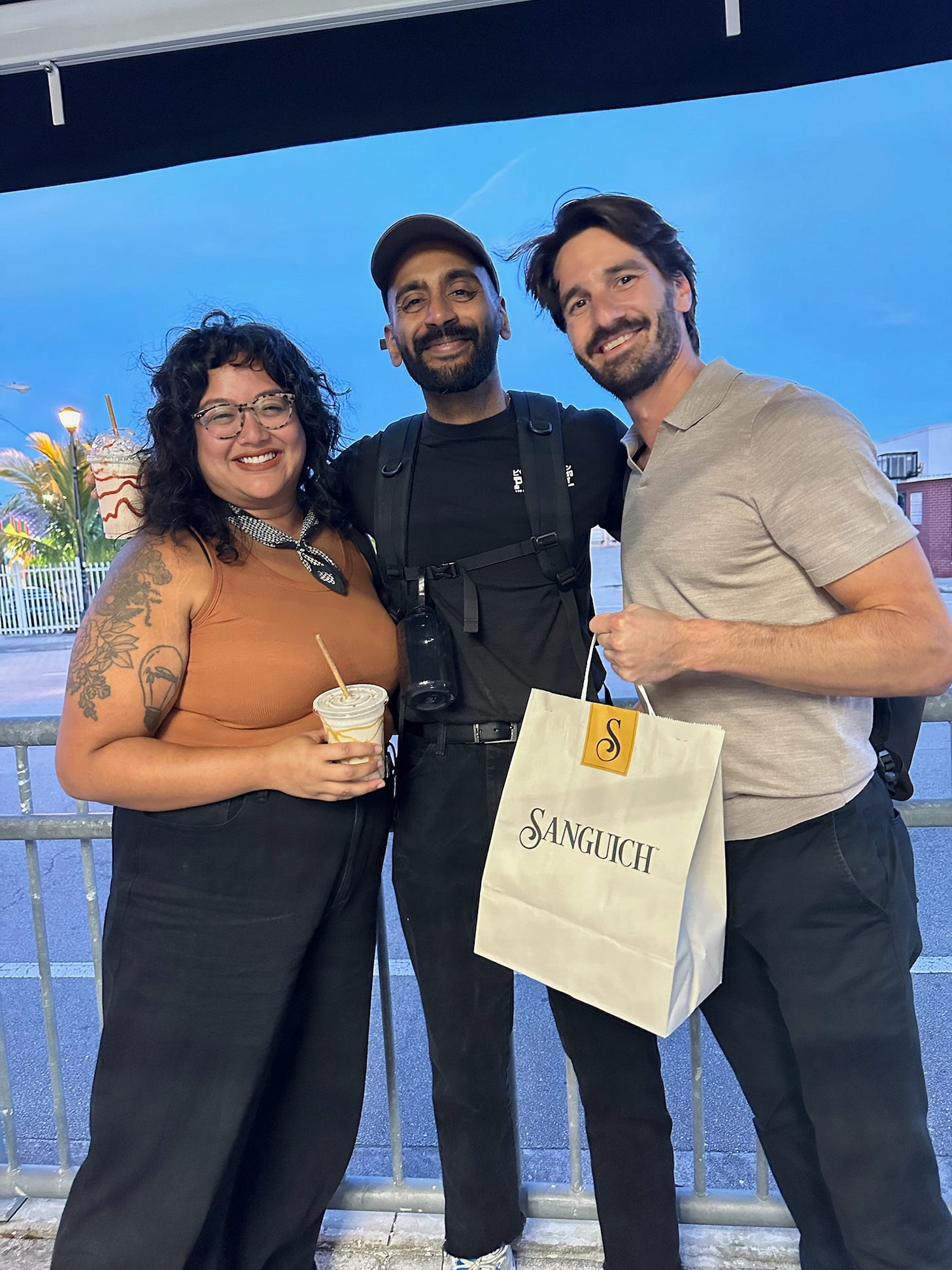 Three NuMarket team members standing while holding a paper bag that reads "Sanguich"