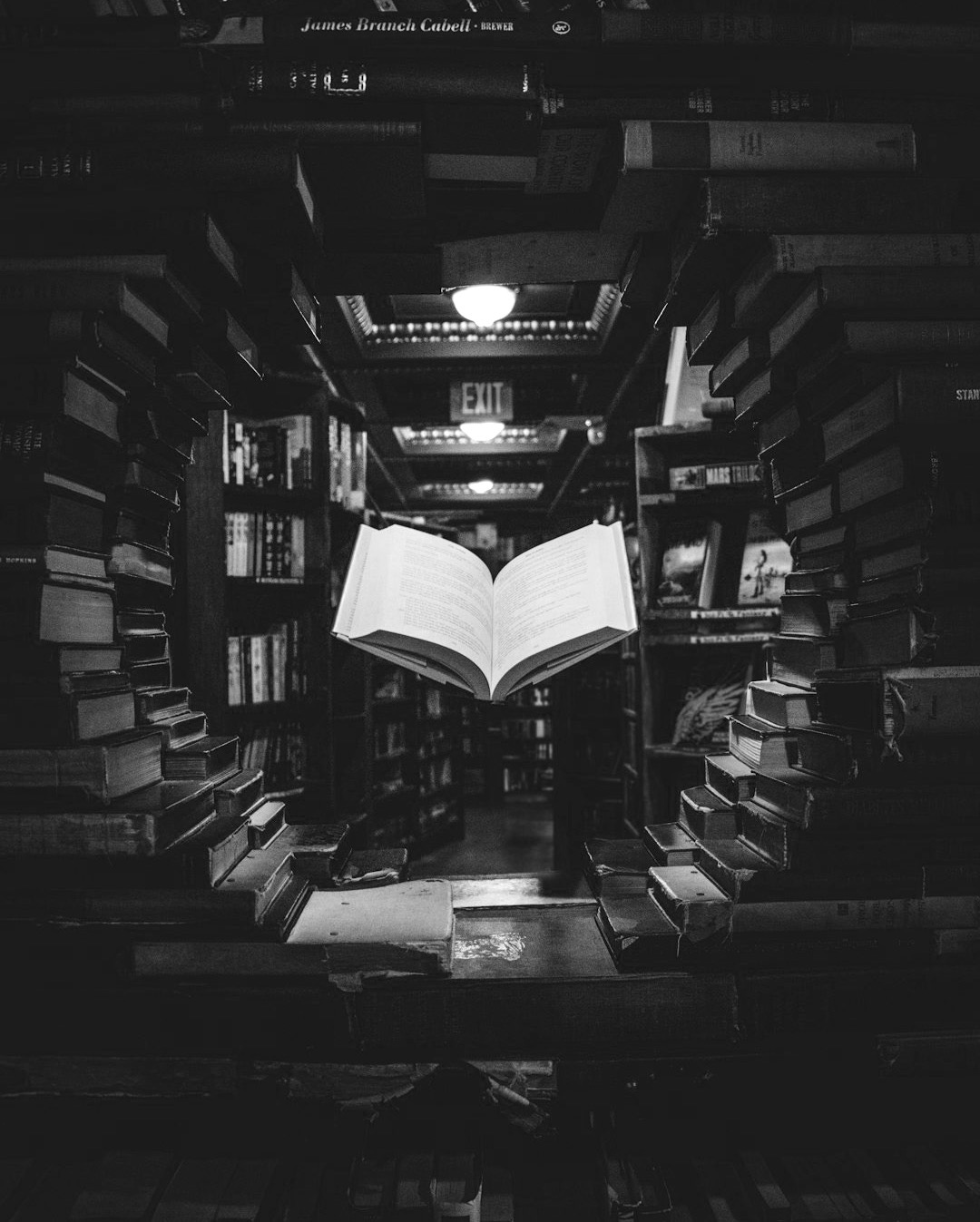 view of floating open book from stacked books in library view of floating open book from stacked books in library