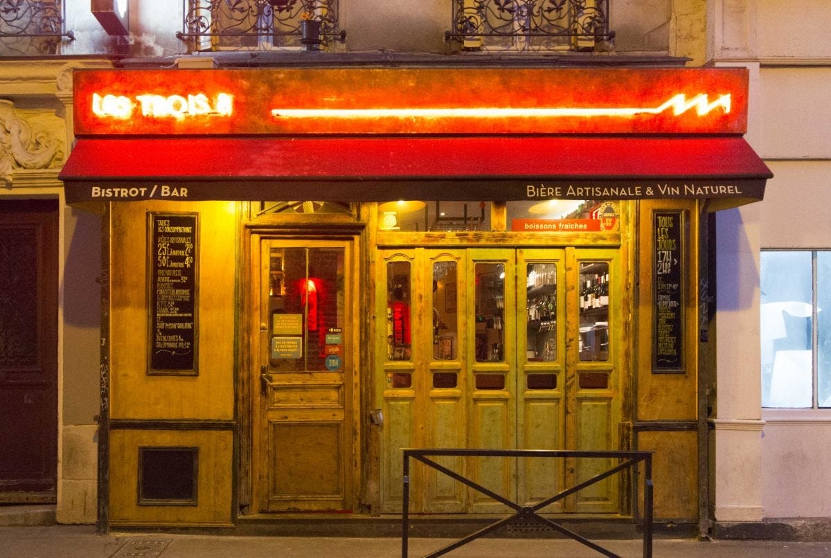 The wooden facade of the bar, with a red canopy and neon signage