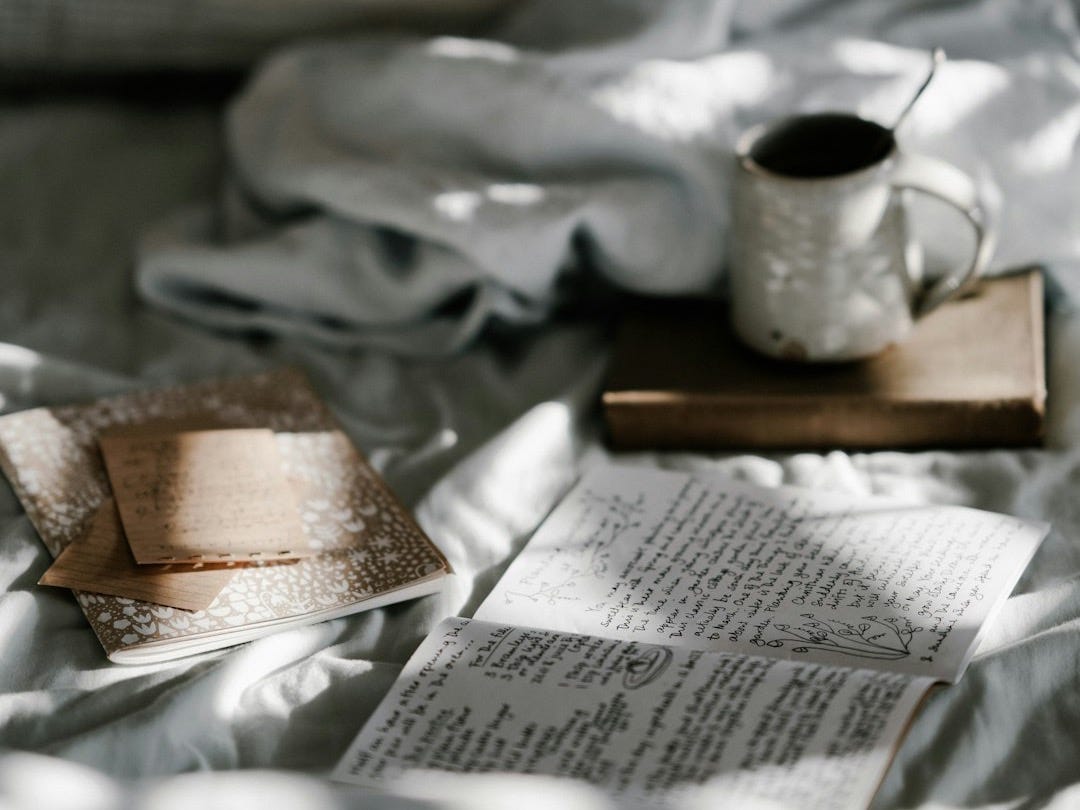 coffee mug on a brown wooden coaster near white blanket