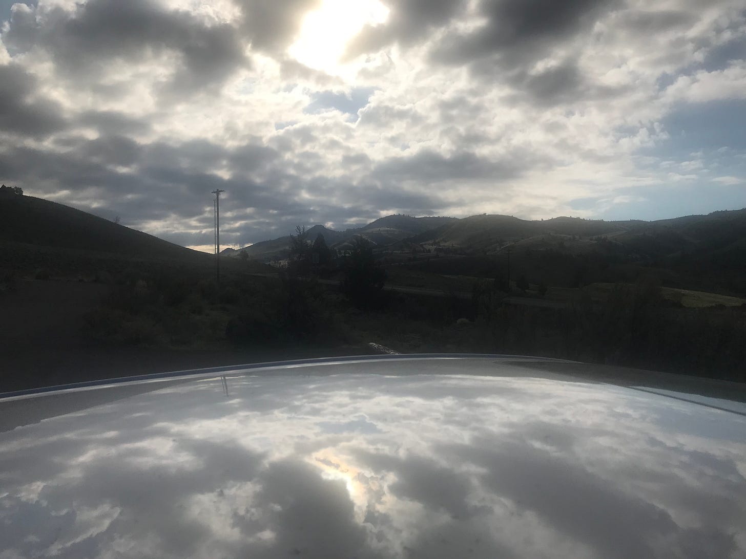 Clouds drift across a mountainous horizon, reflected in a smooth, water-like surface in the foreground.