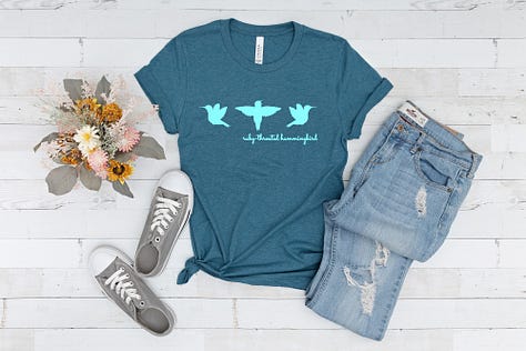 A gallery of three images shows Nature Moments Gear t-shirts in bright colors, featuring the Hummingbird Silhouettes design.