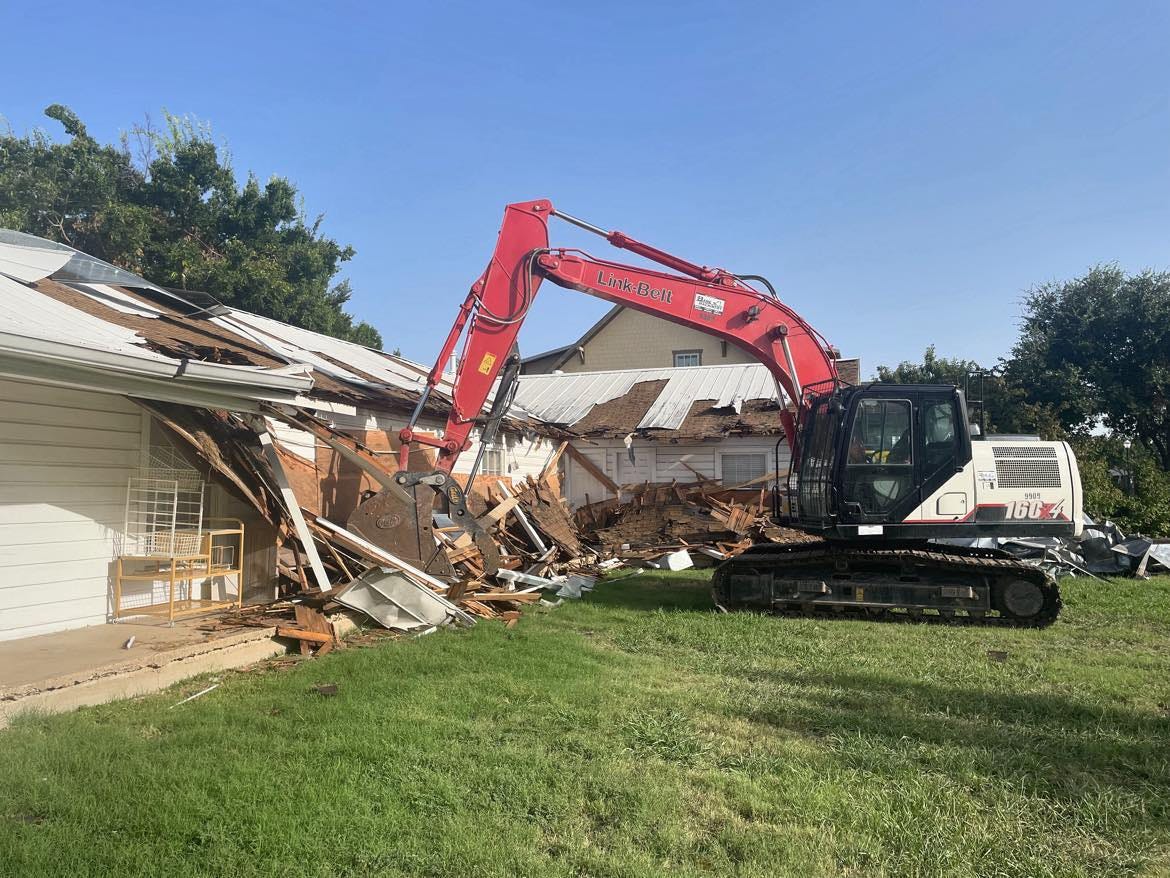An excavator parked next to a building that's being demolished