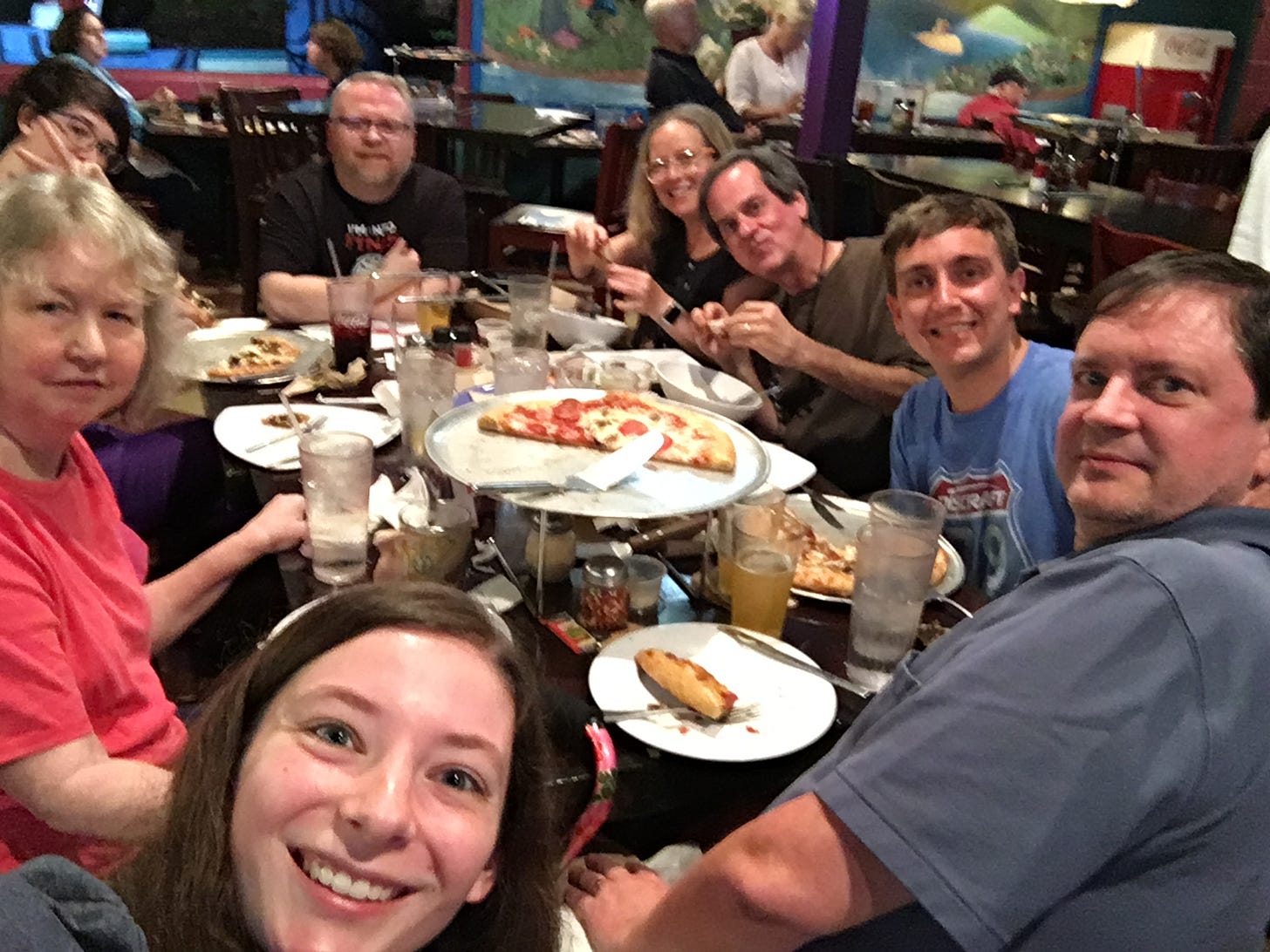 A group of friends eating pizza out.