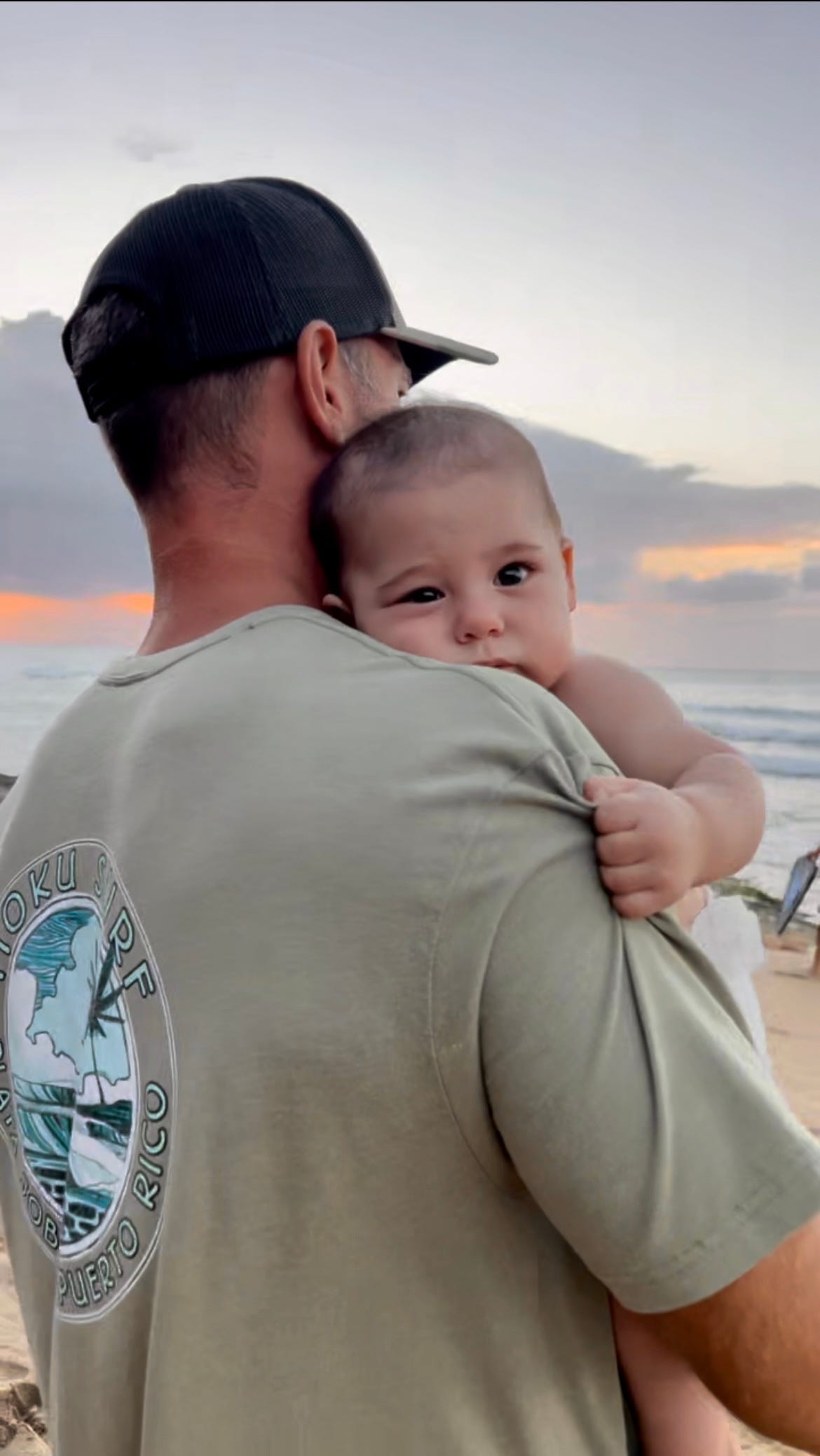 Picture of Nat Sharratt holding baby Sol watching tropical sunset