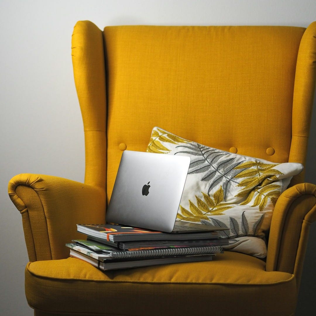 a yellow chair with a laptop on top of it a yellow chair with a laptop on top of it