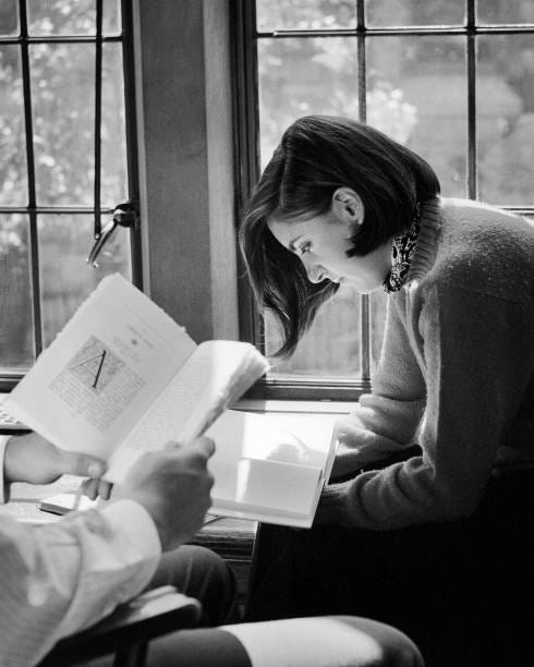 1960s 1970s Female College Student by Window Sunlight Reading A Book Male Student Hand And Book Only