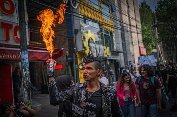 Un hombre con chaqueta de piel con tachuelas y peinado punk sostiene una lata de aerosol en llamas mientras participa en una manifestación. Un hombre con chaqueta de piel con tachuelas y peinado punk sostiene una lata de aerosol en llamas mientras participa en una manifestación.