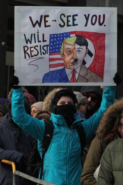 Protestor holds a sign comparing President Donald Trump to Adolf Hitler as thousands of Canadians take part in a massive protest against President...