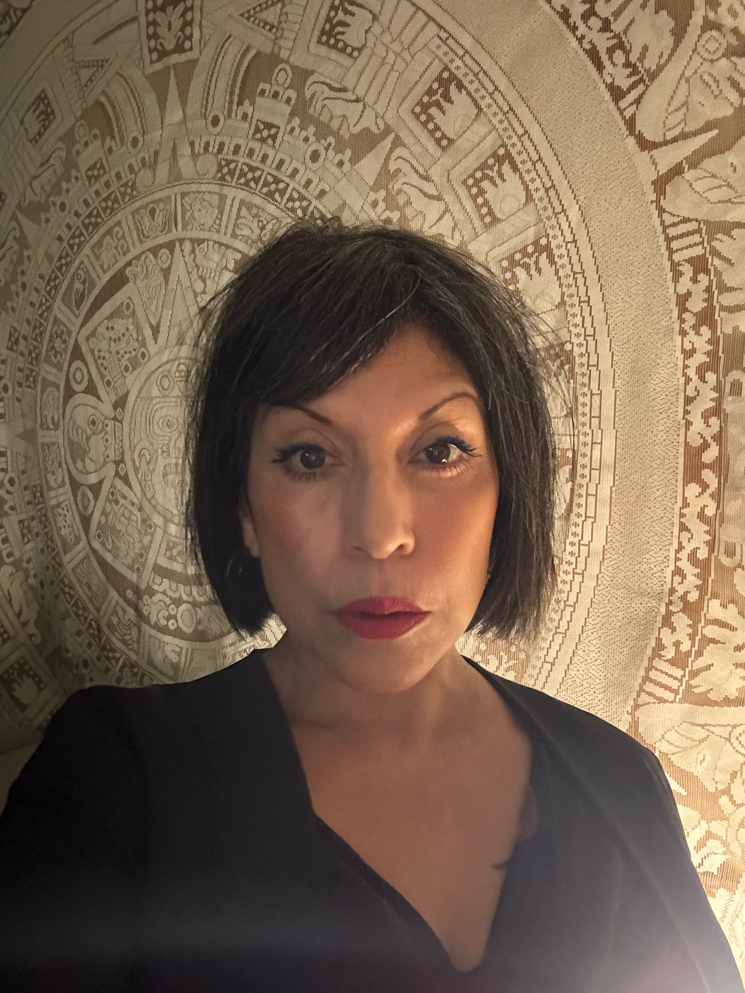 photo of author with black bob haircut in front of aztec calendar design