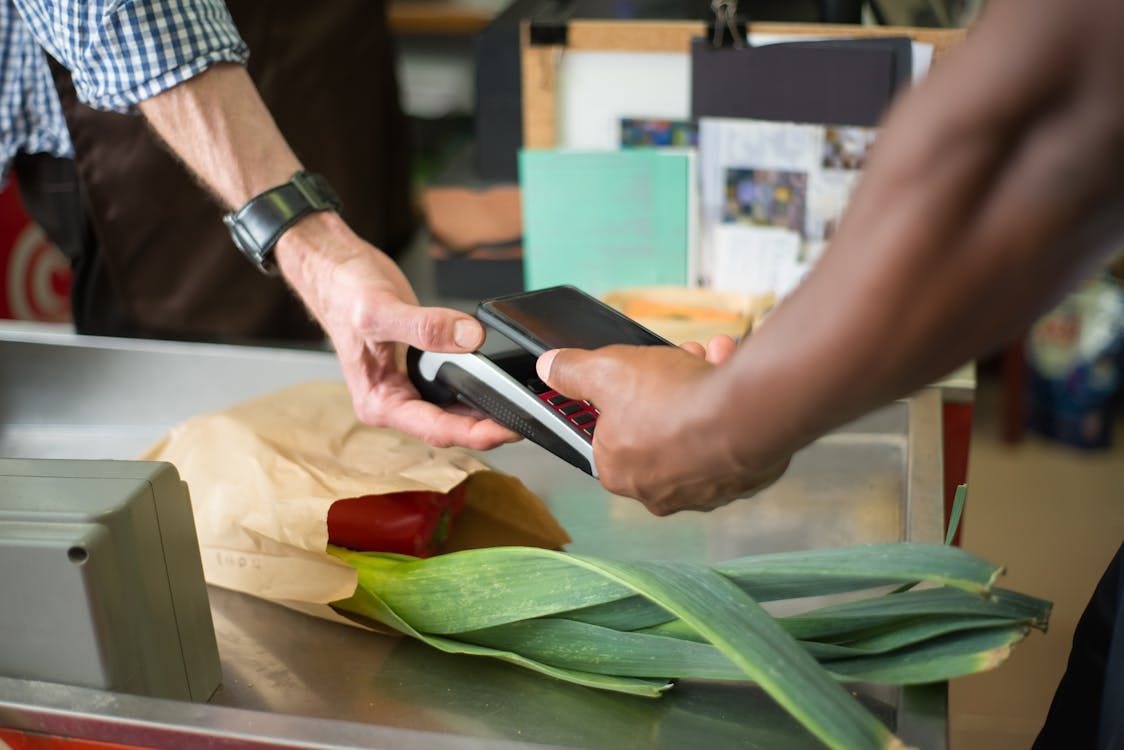 Free A customer making a contactless payment with a smartphone at a grocery store checkout counter. Stock Photo