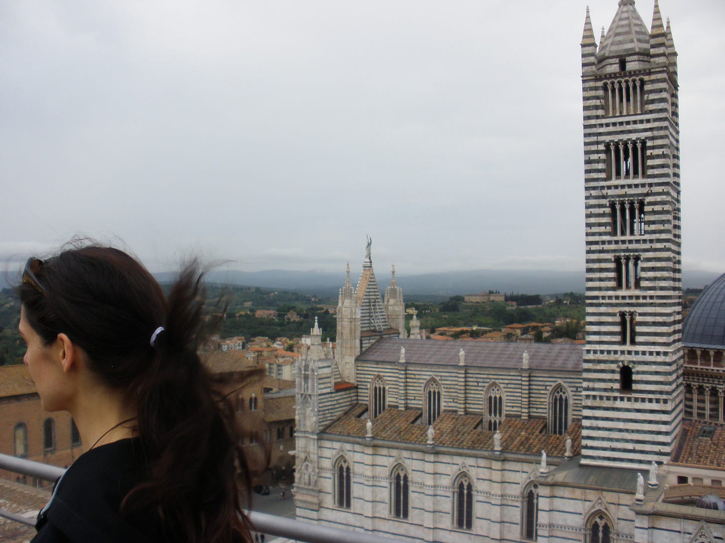 Woman dark hair windy in front of cathedral in Siena