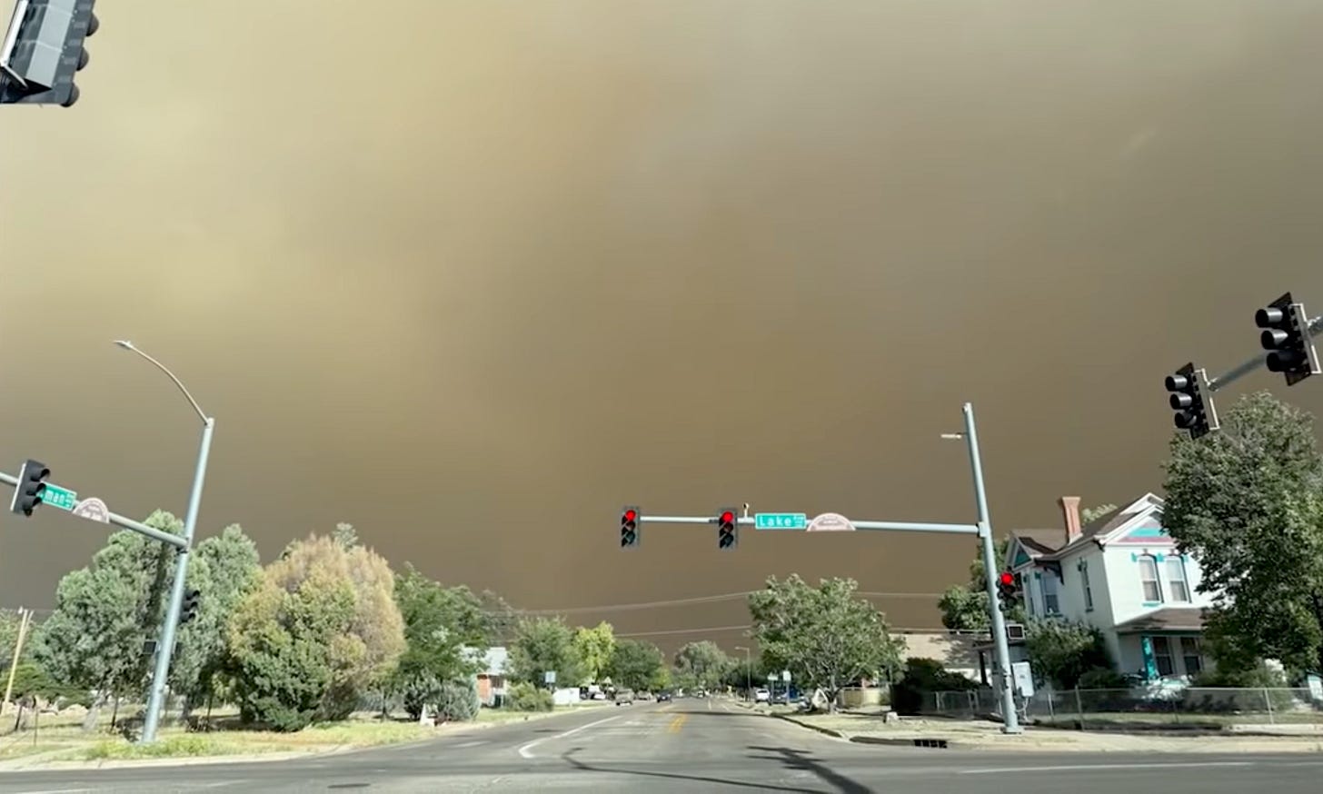 Acrid smoke hovers over a lighted traffic intersection.