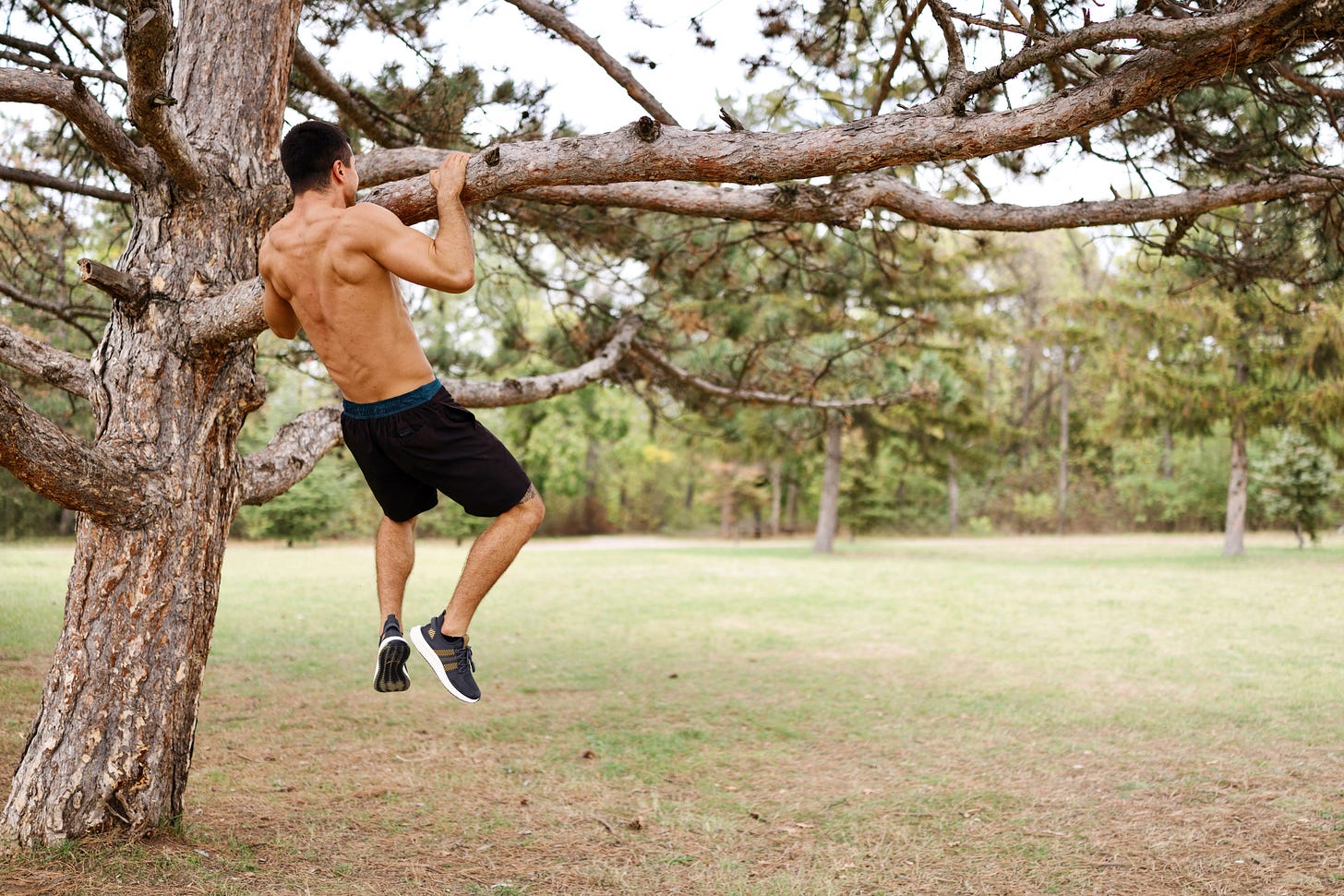 Man doing a pull-up on a tree branch