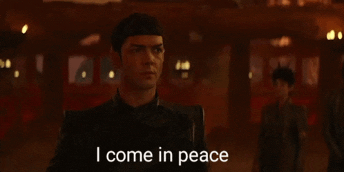 a man is standing in a dark room with the words `` i come in peace '' written on the screen .
