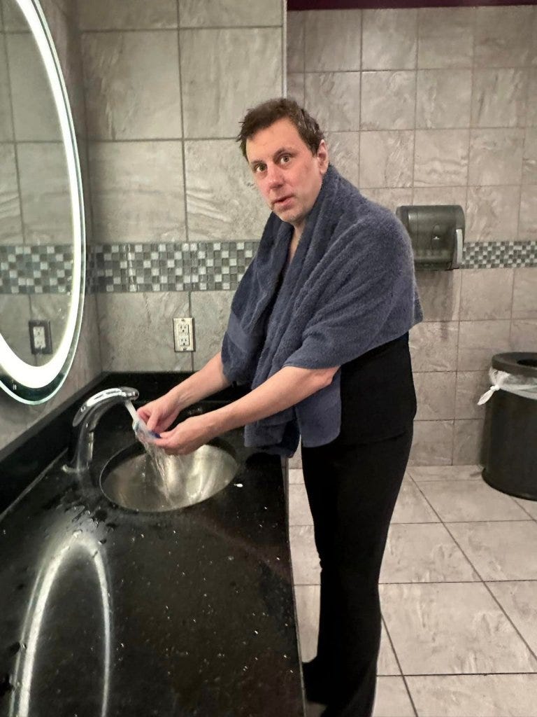 A man with a towel over his head standing in the women's locker room at Planet Fitness in Fairbanks, Alaska