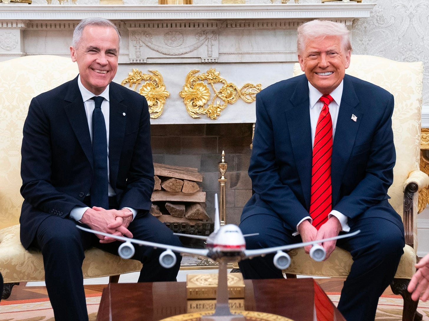 Prime Minister Mark Carney and President Donald Trump smile for a photo while sitting next to each other in the Oval Office, in Washington, D.C.