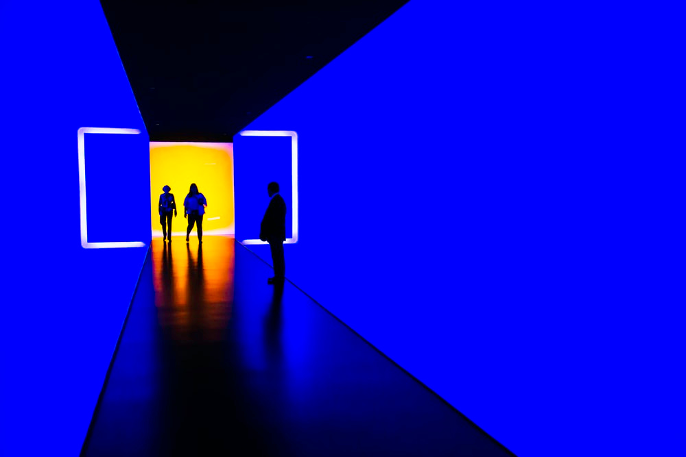 three person standing near wall inside building three person standing near wall inside building