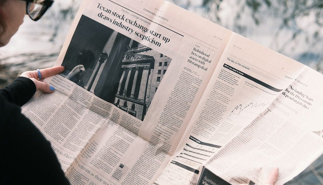 A woman sitting on a bench reading a newspaper