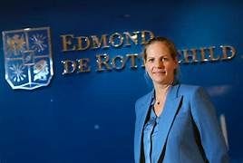 Eine Frau in einem blauen Kostüm steht vor einer Wand mit dem Logo von Edmond de Rothschild. Eine Frau in einem blauen Kostüm steht vor einer Wand mit dem Logo von Edmond de Rothschild.