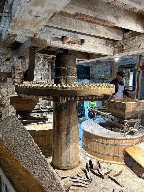 10 photographs showing the inside of Town Mill, Lyme Regis. The milling is done on two floors. On the upper floor the grain is poured into the hopper from where it falls by vibration and gavity down to the millstones below. The grain is then ground and falls into the waiting bag. Flour is sold at the mill and one photo shows bags of flour in plain brown paper bags. Images: Roland's Travels