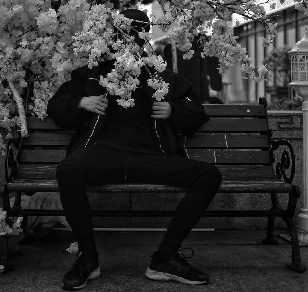 a man sitting on a bench next to a tree