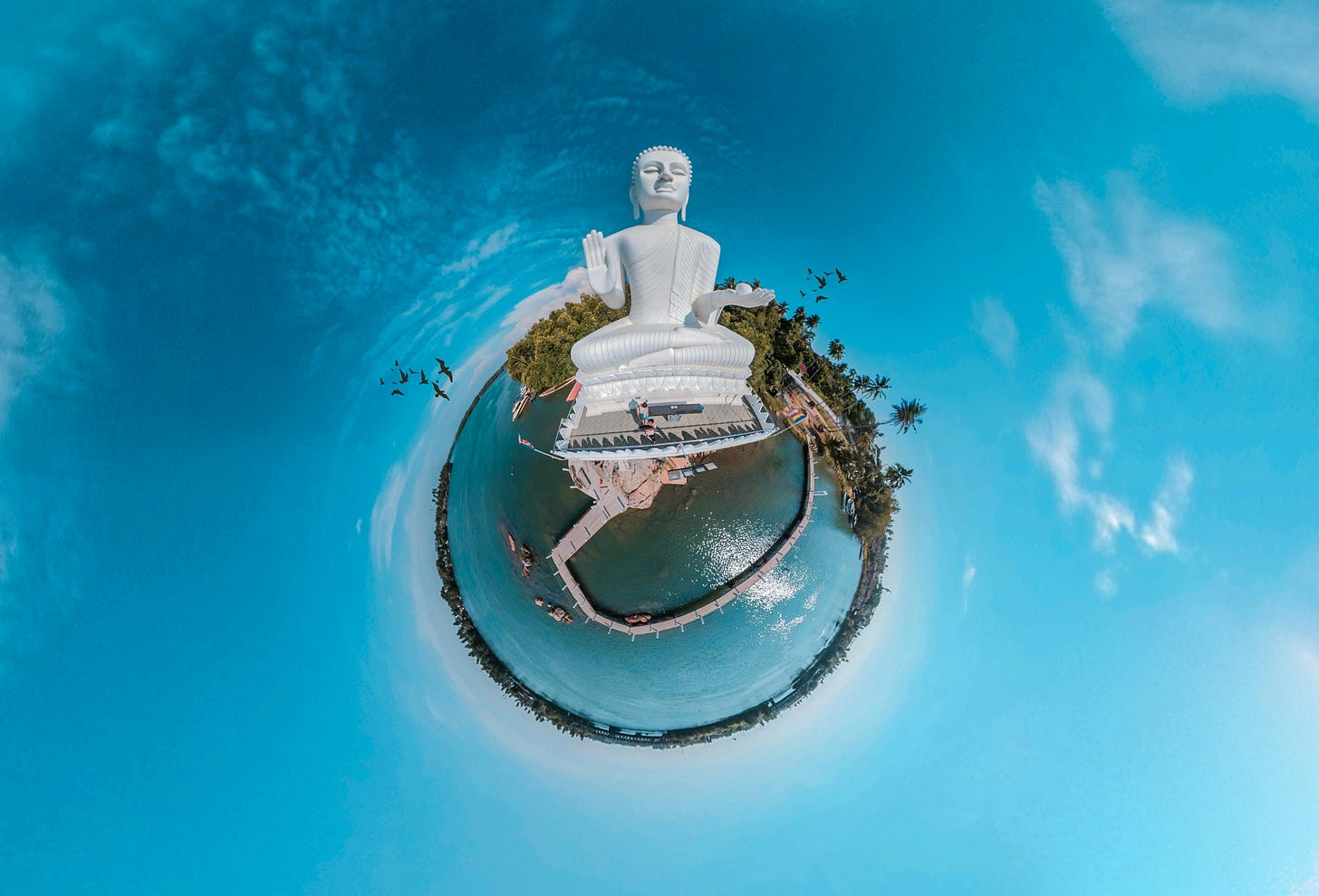 a big white buddha statue on an island taken with a super wide angle lens so the island looks like a planet. a big white buddha statue on an island taken with a super wide angle lens so the island looks like a planet.