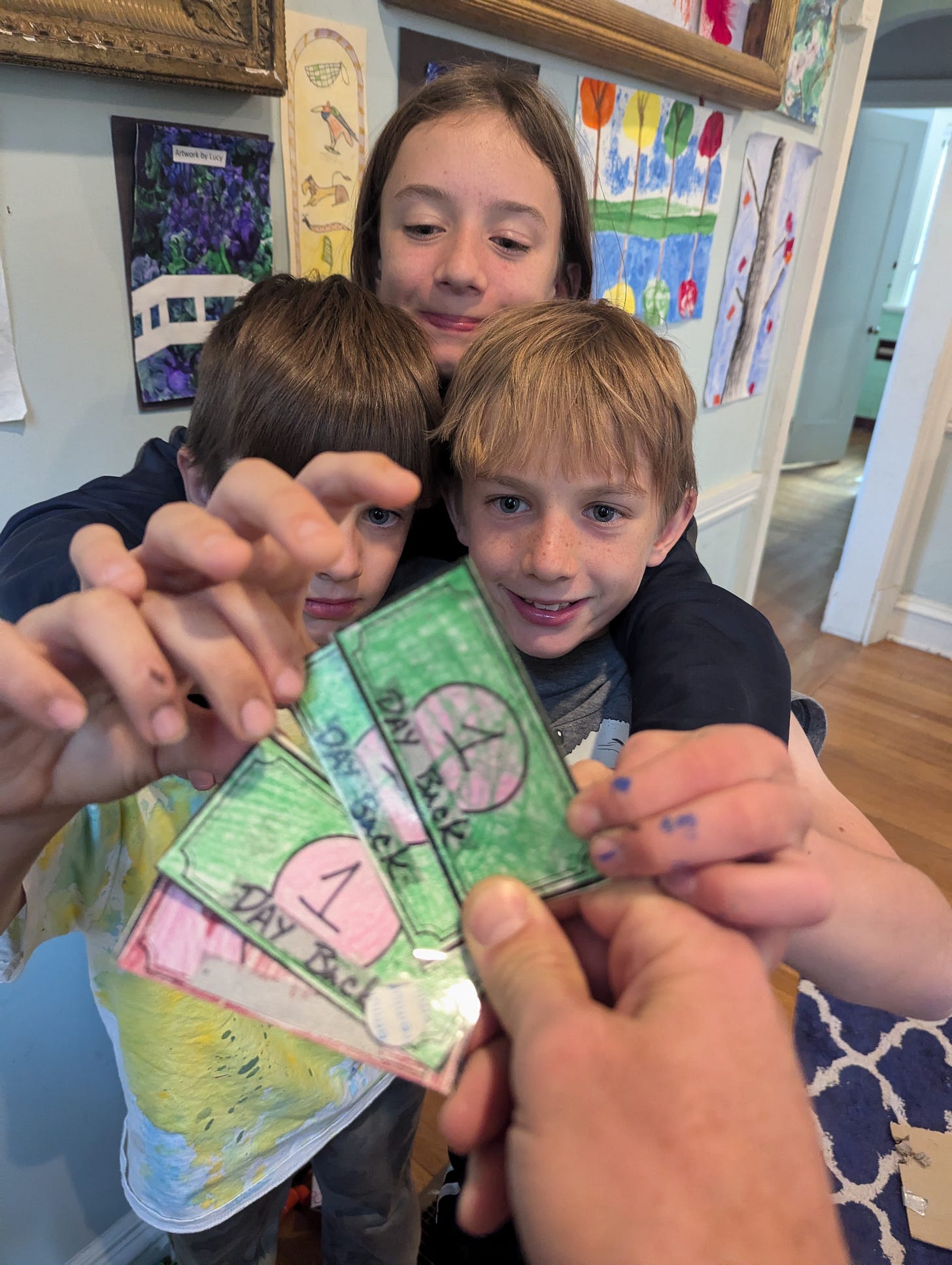 Kids snatch play money from their dad’s hands as he holds it out to them.