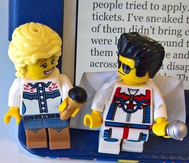 A Lego Dolly Parton minifigure standing next to a Lego Elvis Presley minifigure with my iPad screen behind them. A Lego Dolly Parton minifigure standing next to a Lego Elvis Presley minifigure with my iPad screen behind them.