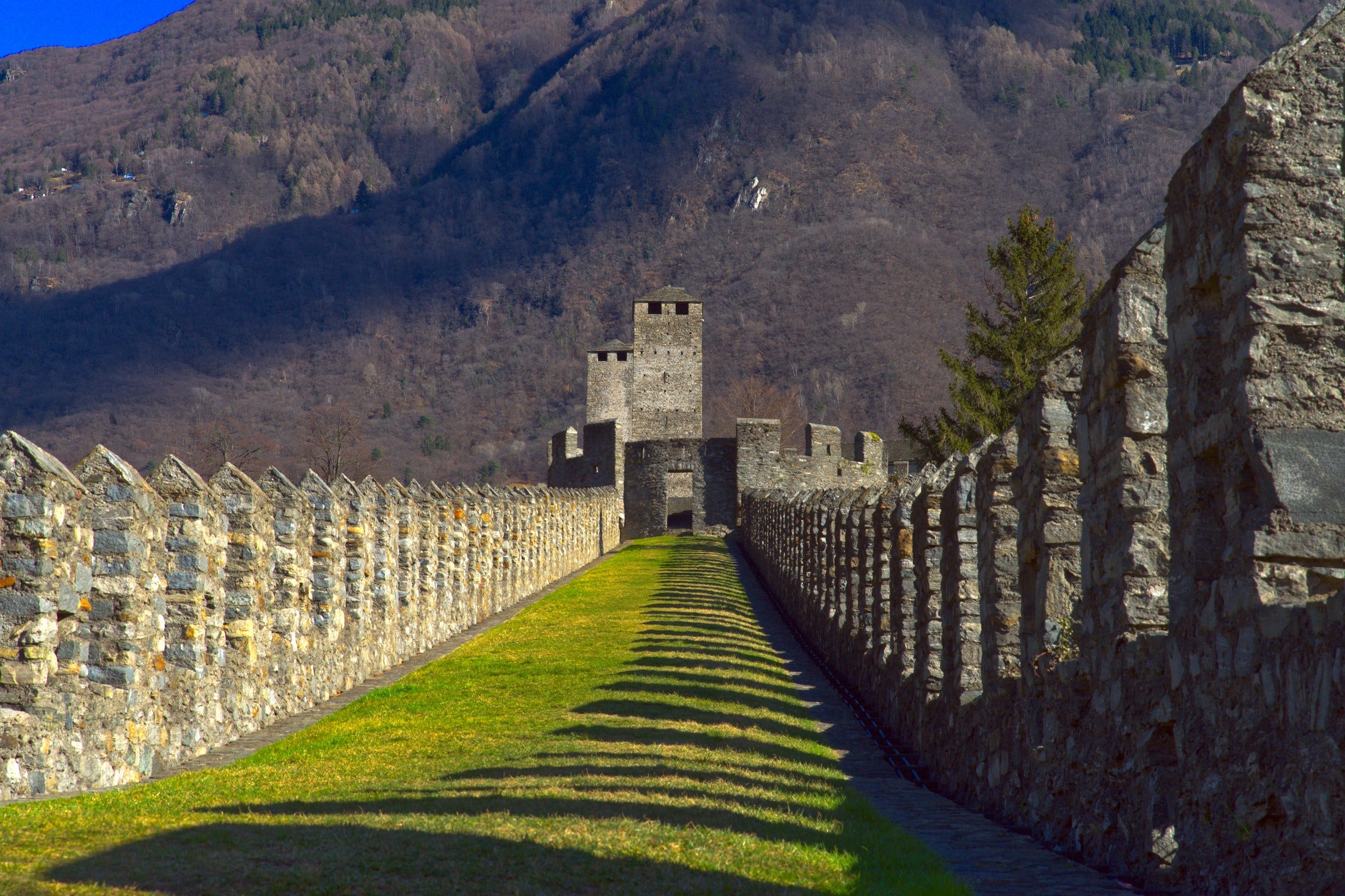 a stone wall and a stone fence with a mountain in the background- by Pix Tresa on Unsplash