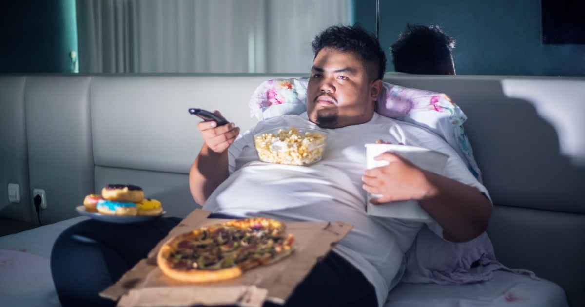 plus size man eating junk food in bed 