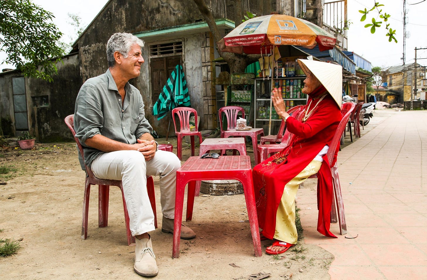 Anthony Bourdain sitting at a table filming Parts Unknown in Vietnam.