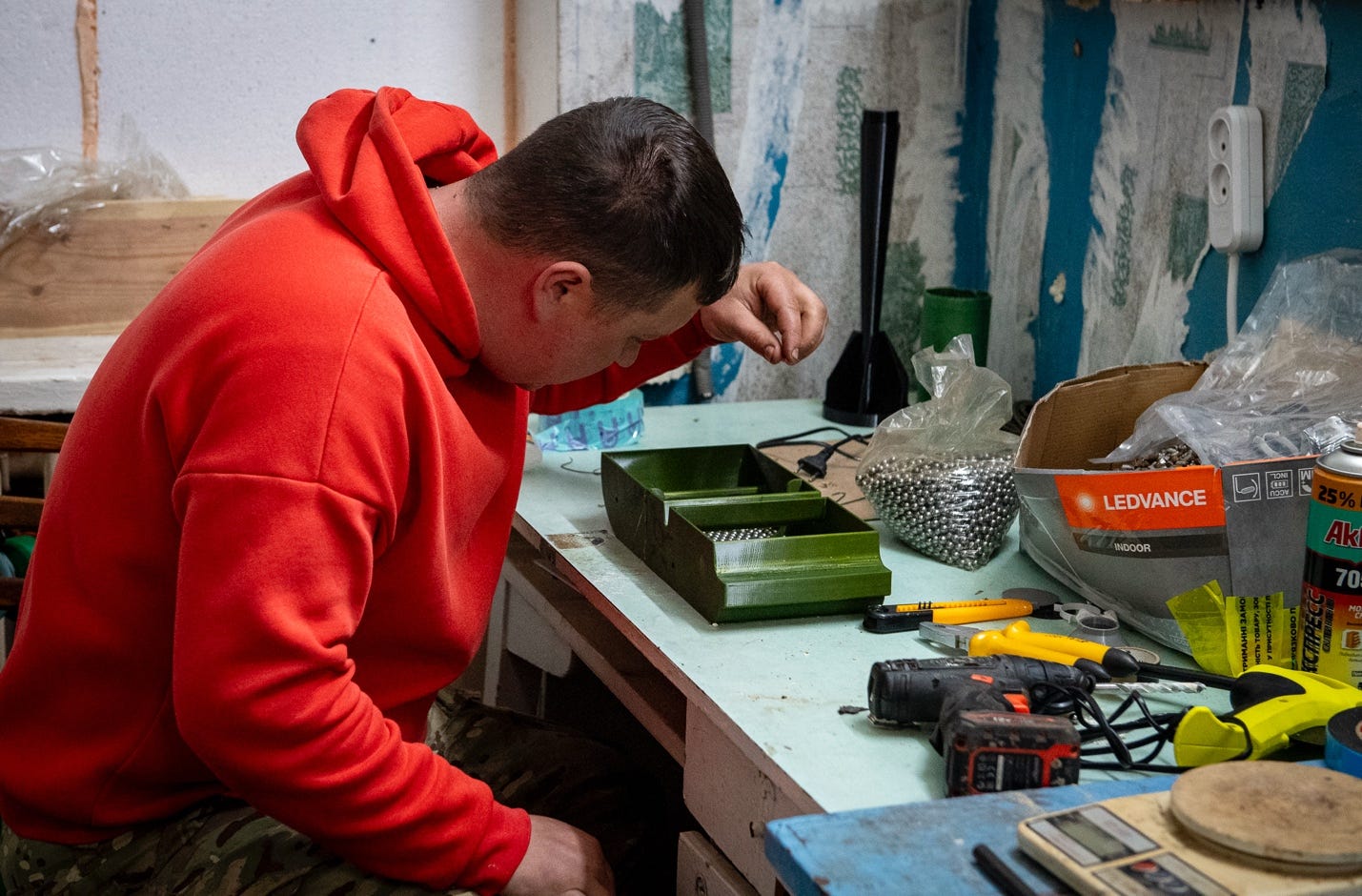 A person in a red hoodie working on a table with tools

AI-generated content may be incorrect.