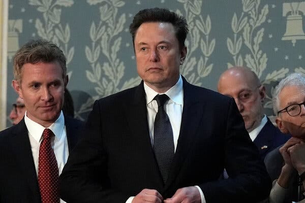 Elon Musk standing in a group of people.
