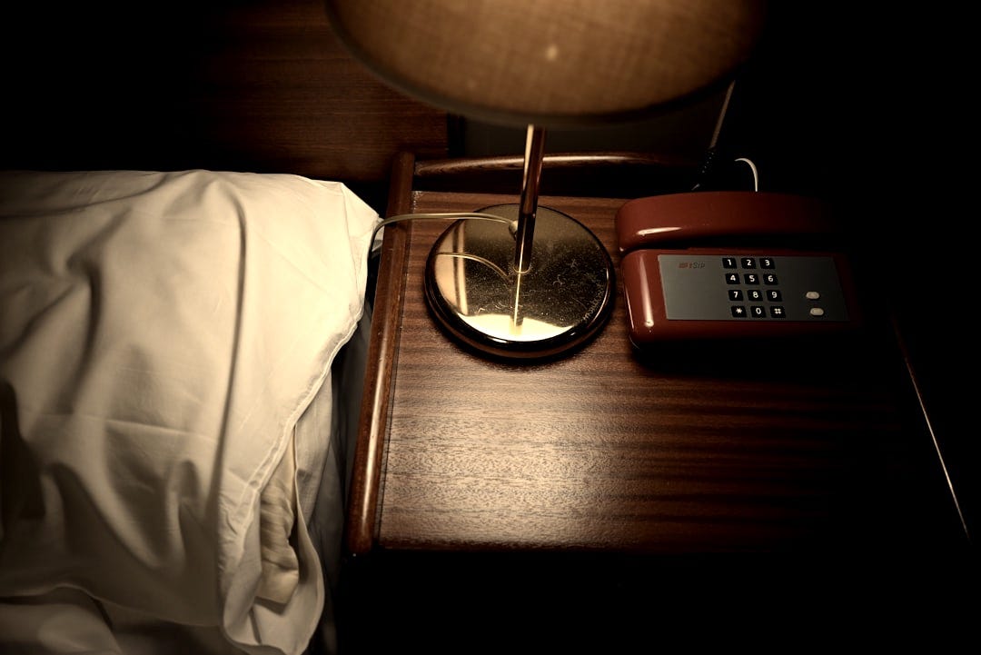 a table with a lamp and a phone on it a table with a lamp and a phone on it