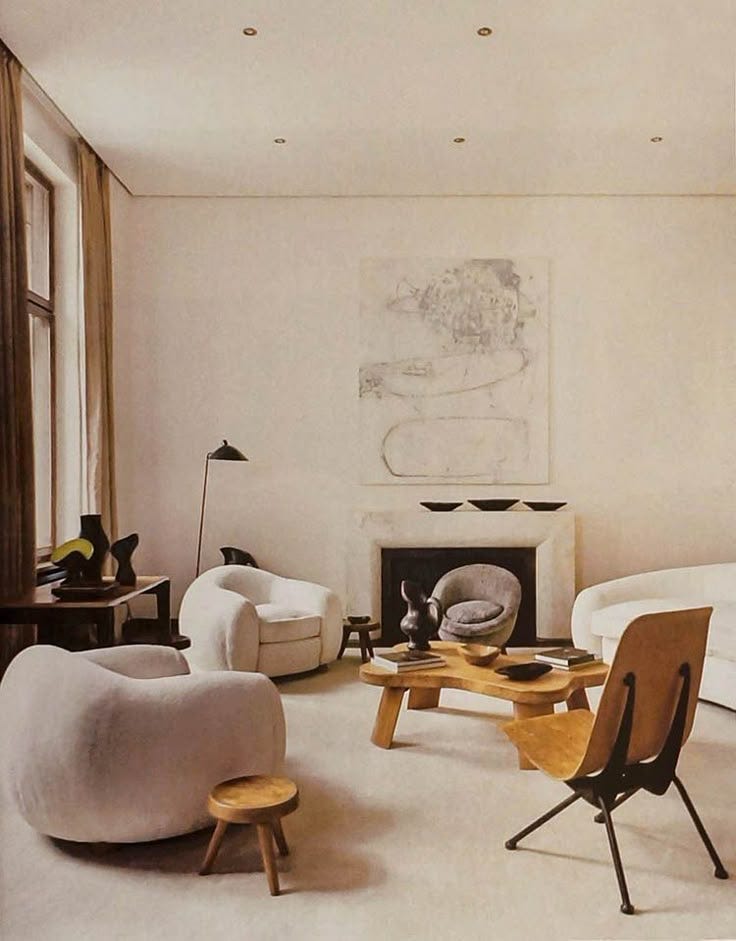 This may contain: a living room filled with furniture and a painting hanging on the wall above it's fireplace