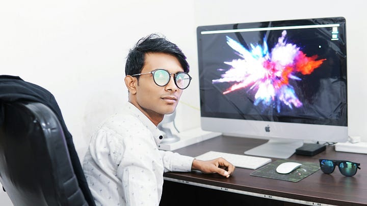 a young entrepreneur sitting at his desktop and looking back at camera