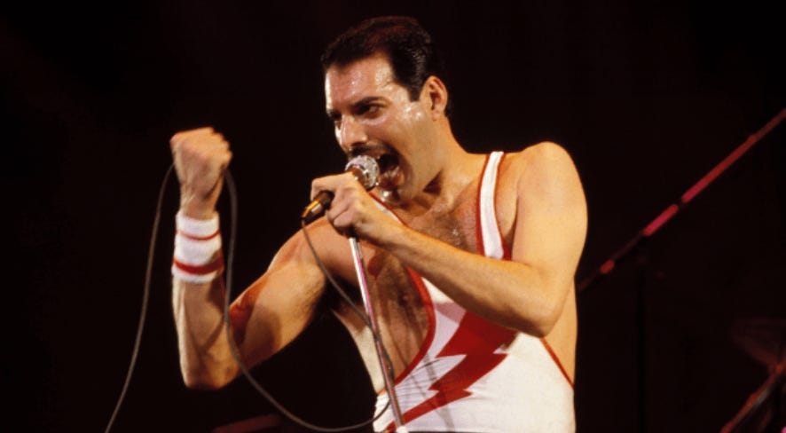 Freddie Mercury being incredible, aka singing into a microphone on stage while the chord is fisted in his other hand not holding the mic. An icon with a mustache.