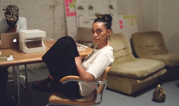 This may contain: a woman sitting on a chair in front of a desk with a computer and printer This may contain: a woman sitting on a chair in front of a desk with a computer and printer