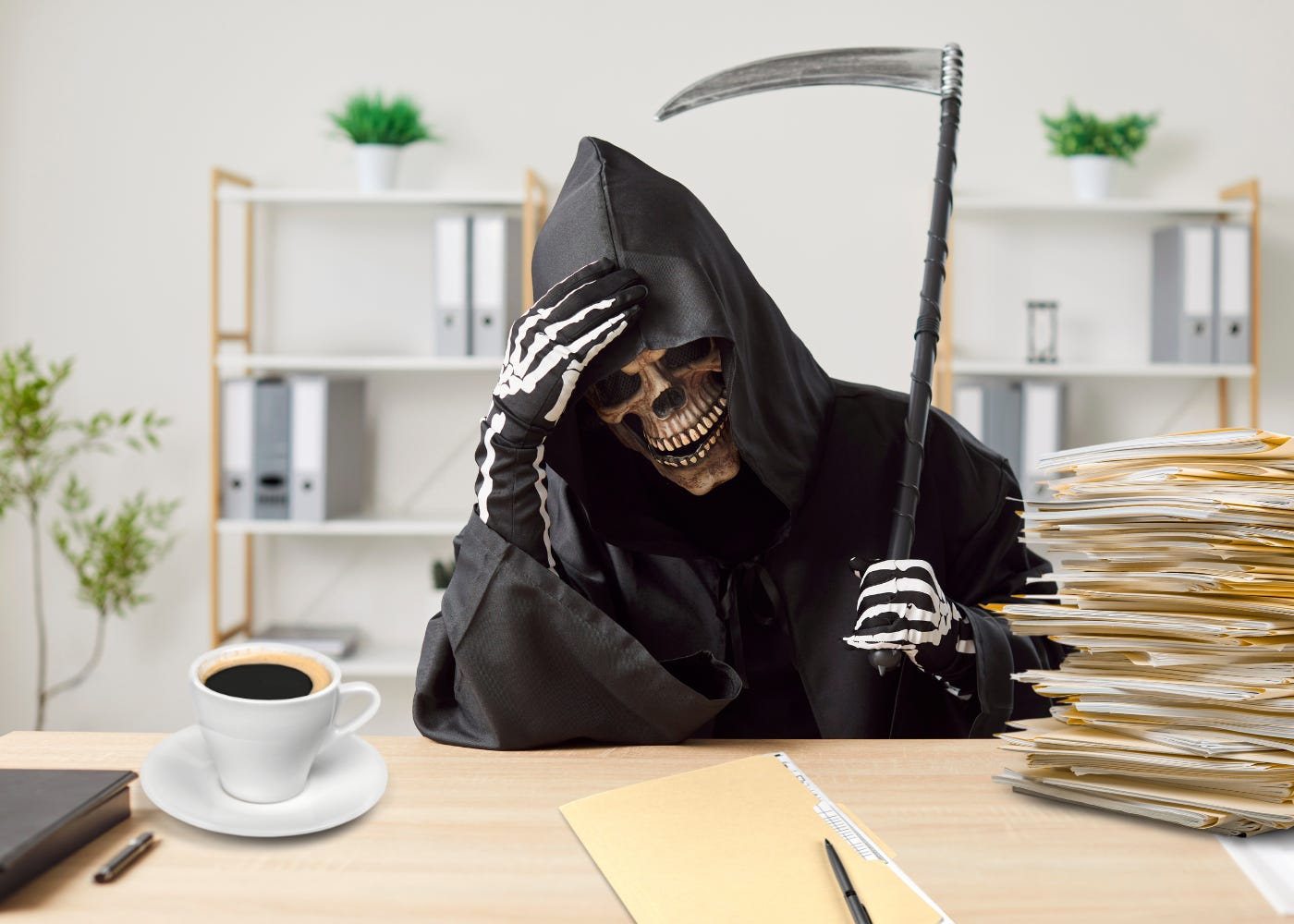 Grim Reaper sits at an office desk expressing annoyance. A folder sits in front of him. There is a messy stack of files next to him and a cup of coffee nearby. Grim Reaper sits at an office desk expressing annoyance. A folder sits in front of him. There is a messy stack of files next to him and a cup of coffee nearby.
