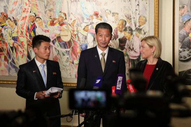Deux ministres, l'un de Corée du Nord et l'autre de Russie, l'air heureux devant une fresque nationaliste de Corée du Nord