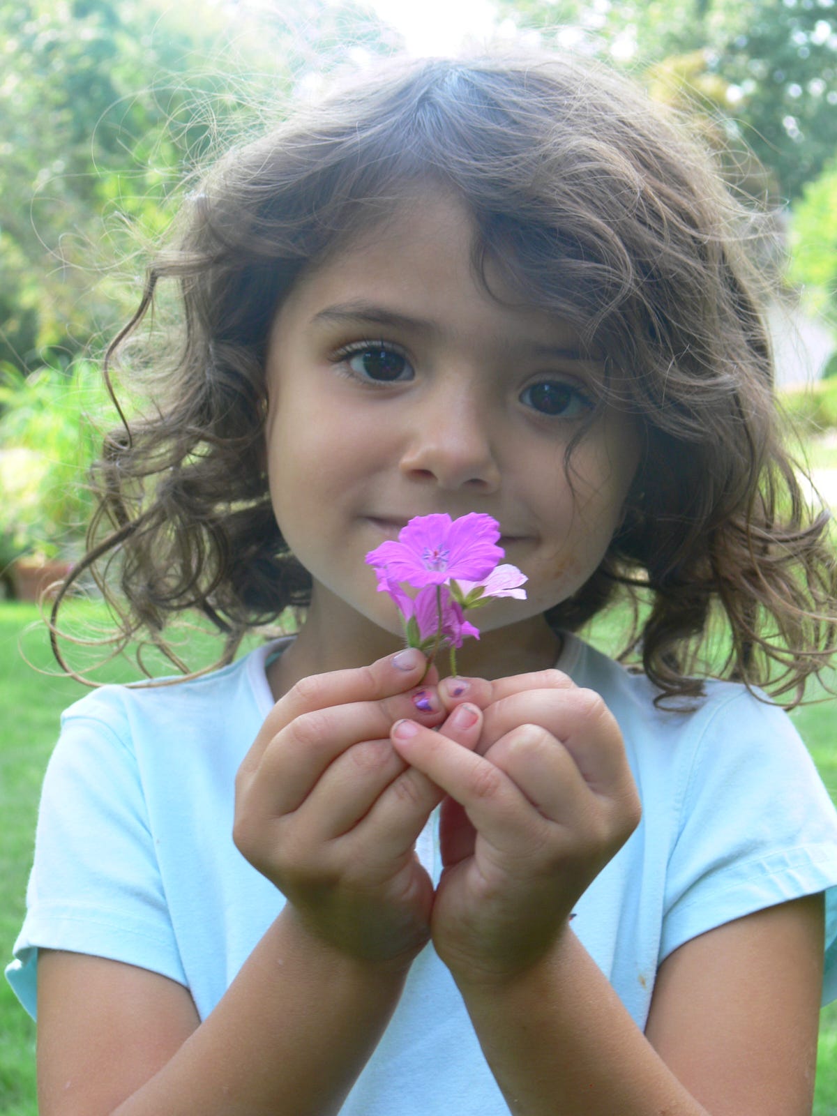 a young girl holding hardy geranium flowers