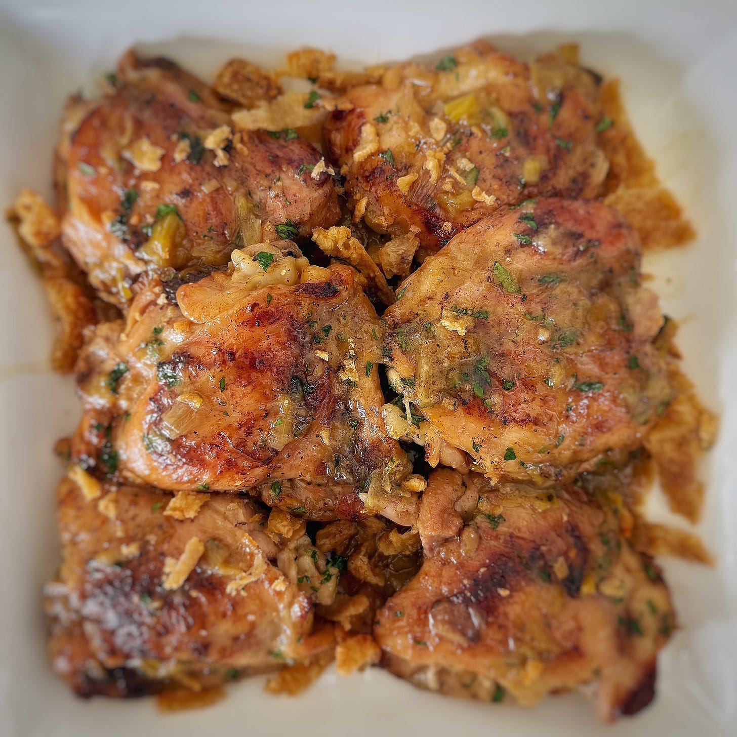 Chicken with 40 pieces of garlic served on a white platter. 