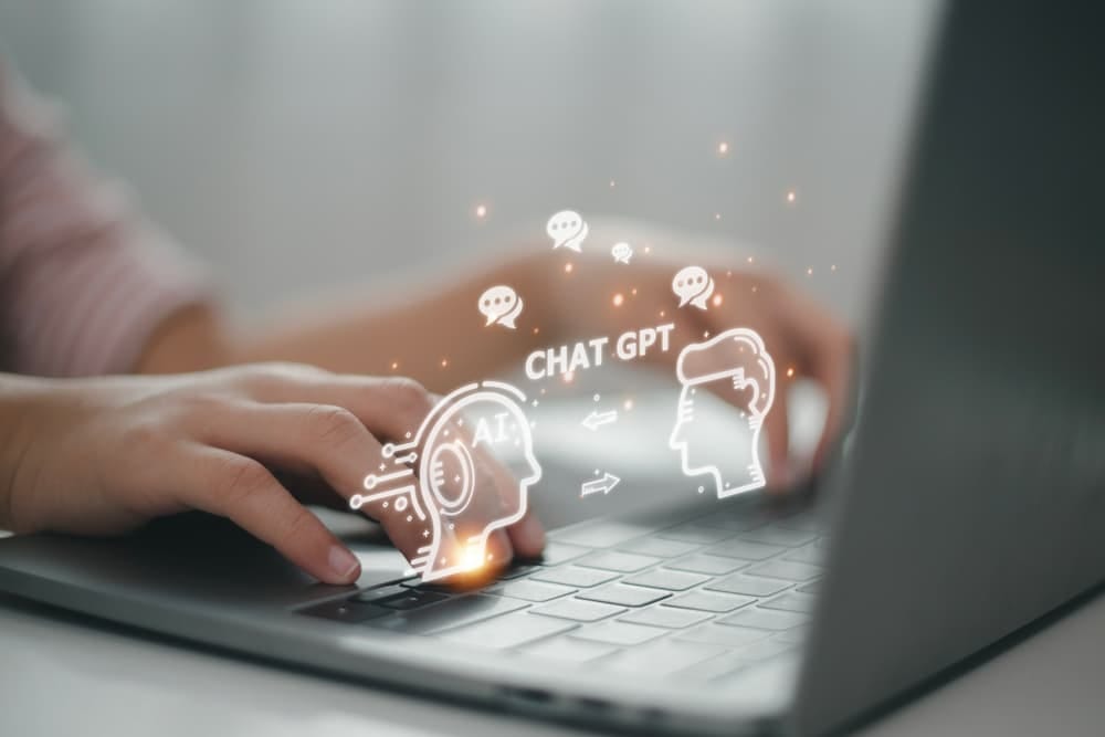 Digital representation of human-AI interaction, with a person typing on a laptop and overlaid graphics of AI and human heads with "CHAT GPT" between them