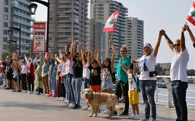 Anti-government protesters form a human chain as a symbol of unity, during ongoing protests against the Lebanese government, on the Mediterranean waterfront promenade, in Beirut, Lebanon, Oct. 27, 2019 (AP Photo/Bilal Hussein)