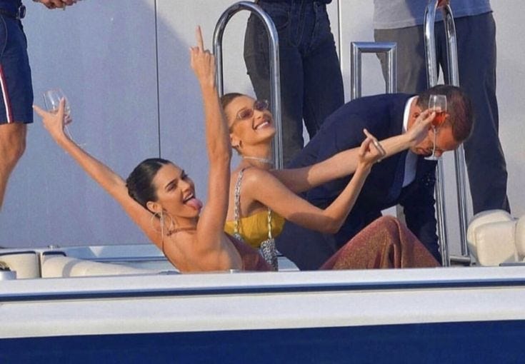 This may contain: two women and a man are sitting on a boat in the water with their arms up