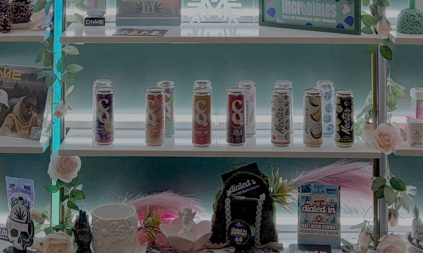 An array of colorful beverage cans containing THC-infused drinks is on a shelf surrounded by other display ads, curios, and products for sale.