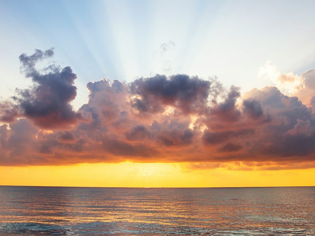 man raising his arms on sea under black clouds