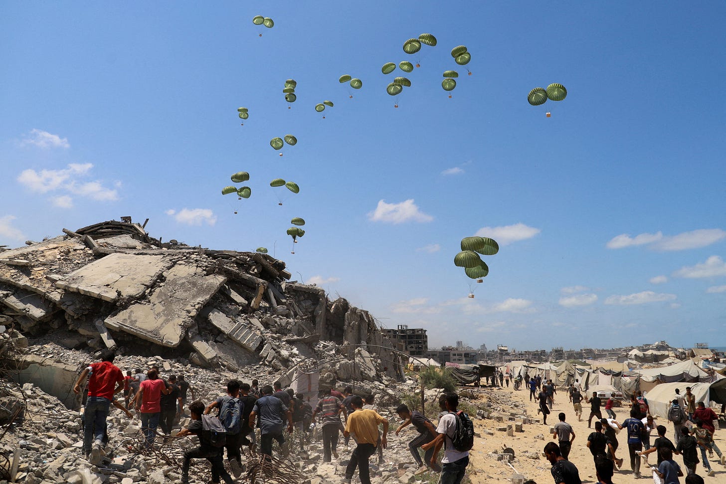 Palestinians run towards parachutes carrying aid packages airdropped over northern Gaza Strip, August 7, 2025. R