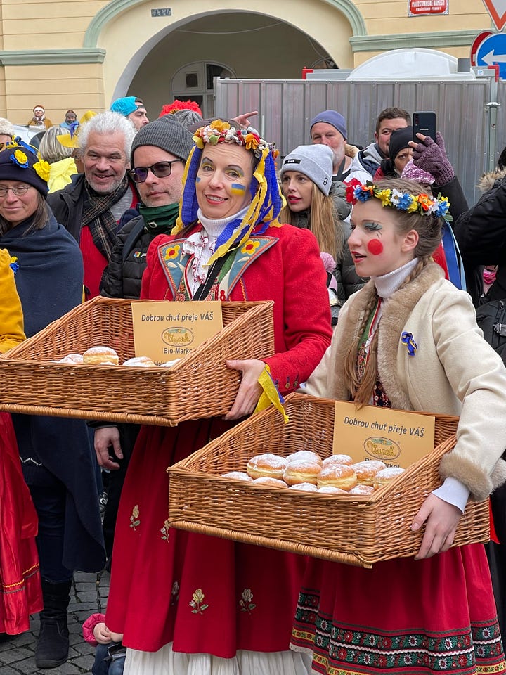 Freshly fried koblihy (Czech carnival doughnuts) being handed out to festival-goers during Masopust.
